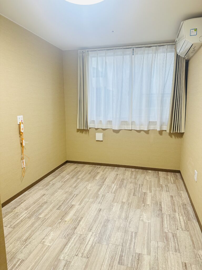 明るい窓とナースコールのある居室の様子